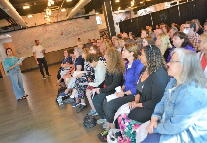 Two presenters speak in front of a group of people during an educational session.