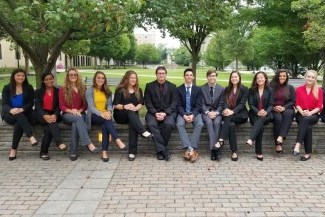 Photo of high school students in business clothes sitting on a wall at Canisius University